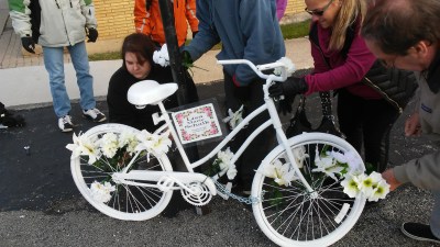 Mourners place flowers on the ghost bike for Lisa Schalk. Photo: Chicago Ghost Bikes