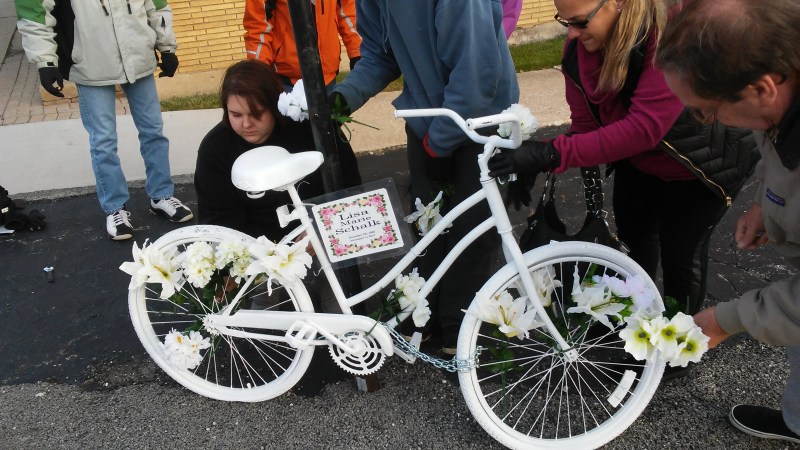 Mourners place flowers on the ghost bike for Lisa Schalk. Photo: Chicago Ghost Bikes