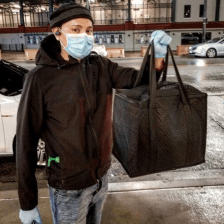 A Postmates driver picks up an order across the street from Wrigley Field in protective gear. Photo: Jared Haberman
