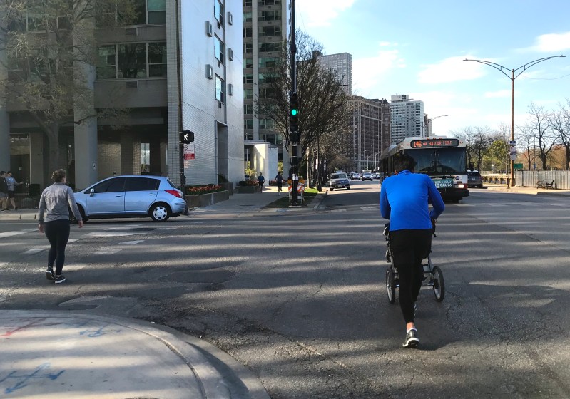 To maintain social distance while the Lakefront Trail is closed, a father pushes his child in a jogging stroller in the street on Inner Lake Shore Drive. Photo: John Greenfield