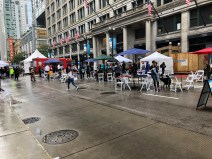 A few folks enjoying the seating area along State St. A few vendor tents are in the background.