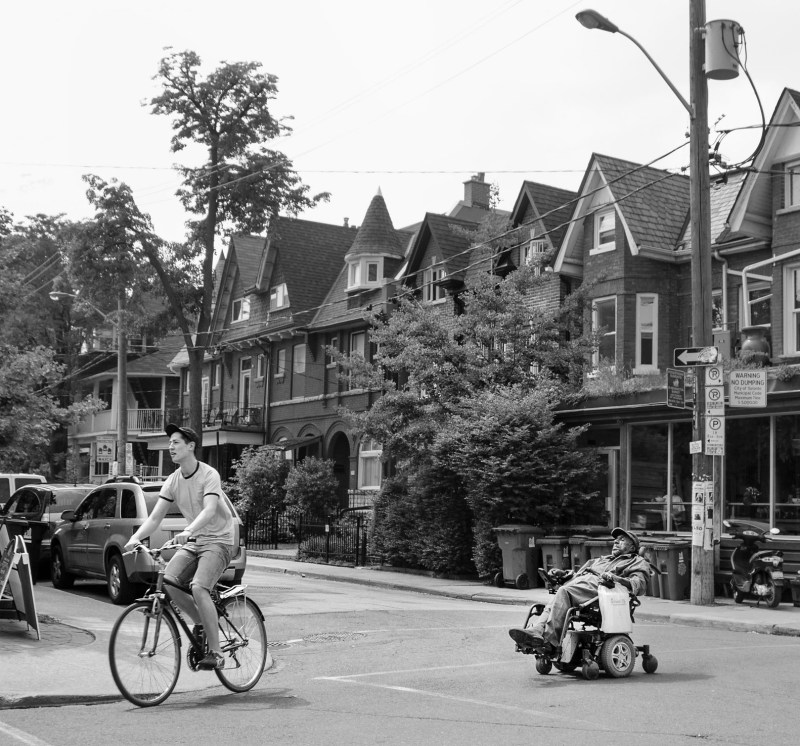 A person biking and a person using a wheelchair in Toronto's Kensington Market. Photo: Eric Parker