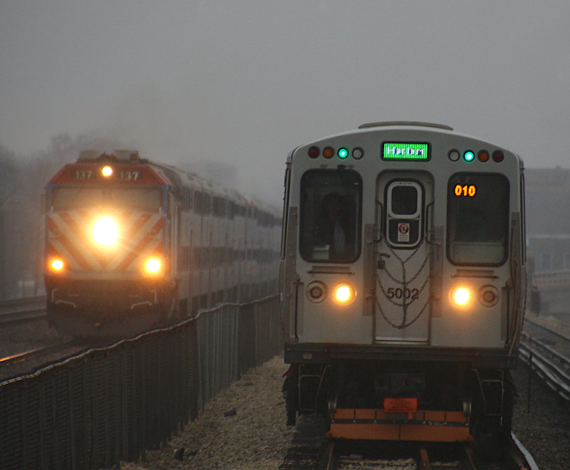 A Metra Union Pacific West train and a CTA Green Line train cross paths on Lake Street. Photo: Jeff Zoline