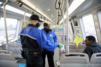 BART Transit Ambassadors give a mask to a passenger and ask him to wear it. Photo: BART