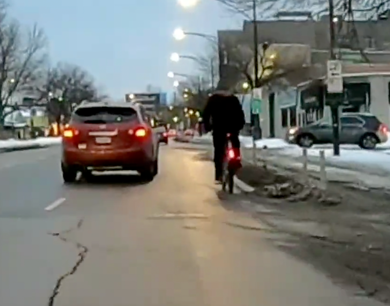 A Divvy user rides outside of the Clark Street protected bike lanes in Edgewater because they're clogged with snow and illegally parked vehicles. Image: Twitter user @Teflonics