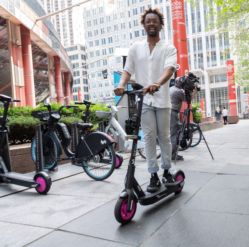 Riding one of the new Divvy scooters at the Thompson Center ribbon-cutting. Note the silver triangle at the front of the scooter for securing it in a docking station. Photo: CDOT