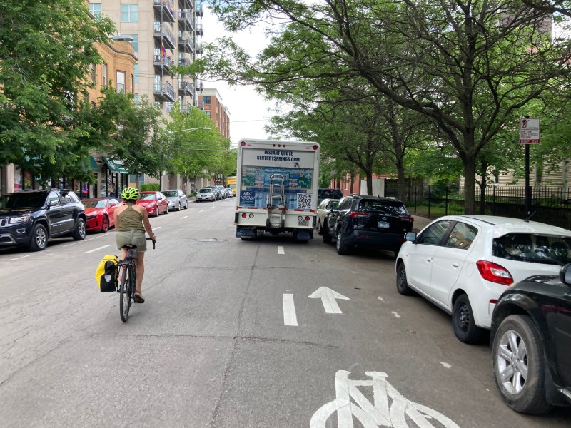 A bike rider is forced to ride in the mixed-traffic lane on Leland, near where an illegally parked ComEd truck contributed to the death or Lily Shambrook, 3, last week, because a Century Springs water delivery truck is parked in a bike lane. Photo: John Greenfield